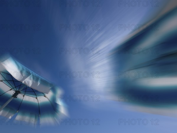 Parasols in front of a blue sky with clouds, zoom effect