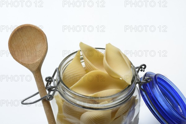 Conchiglione in glass jar with cooking spoon, Italian pasta variety