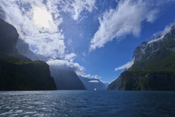 Dramatic scenery with water and cloudy sky between rock faces, summer, Milford Sound, Te Anau,