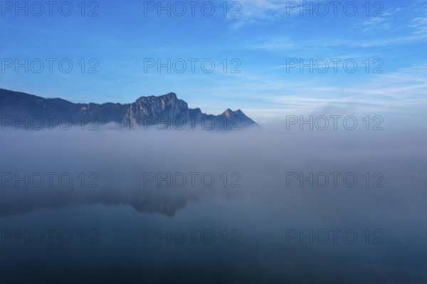Drone shot, morning fog at Mondsee in autumn with Drachenwand, Salzkammergut, Upper Austria,