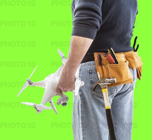 Partial view of construction worker wearing toolbelt and holding his UAV drone on green screen