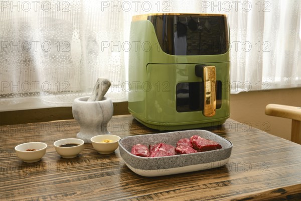 Fresh cuts of beef steaks sit on a wooden table next to bowls of spices and sauces ready to be