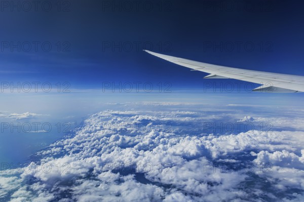 Above the clouds over the Indian Ocean. On the left, the coast of India. View from the aircraft