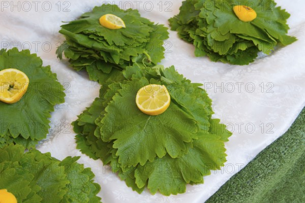 Green leaves artistically decorated with lemon halves, laid out on a table, vine leaves, market,