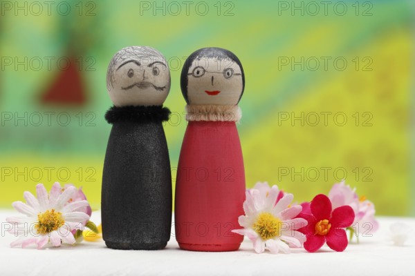 Funny painted wooden cone man and woman in front of a colourful painted background, North