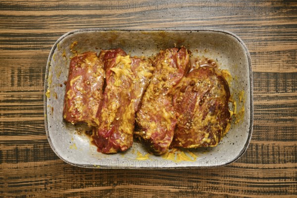 Overhead view of raw beef flat iron steak marinated in mustard, soy sauce and spice blend in