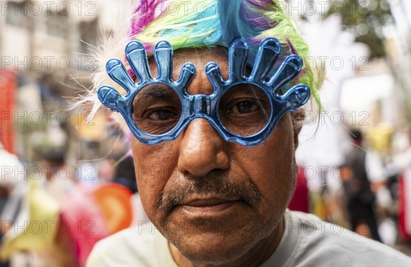 A person wears a holi sunglass in a market on the eve of Holi Festival, on March 13, 2025 in