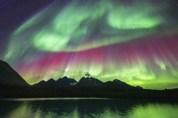 Northern lights over Bergen in the Lyngen Alps, reflection on the lake, Troms og Finnmark, Norway,