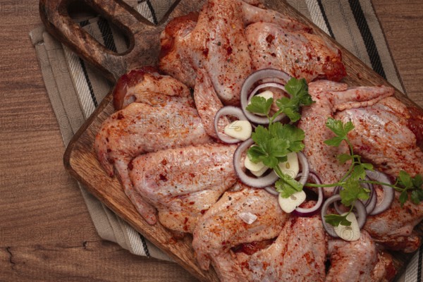 Chicken wings, marinated and laid out on a wooden platter, ready for cooking, grilling or baking,