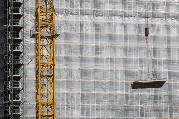 Essen, North Rhine-Westphalia, Germany - Construction crane lifts concrete section in front of