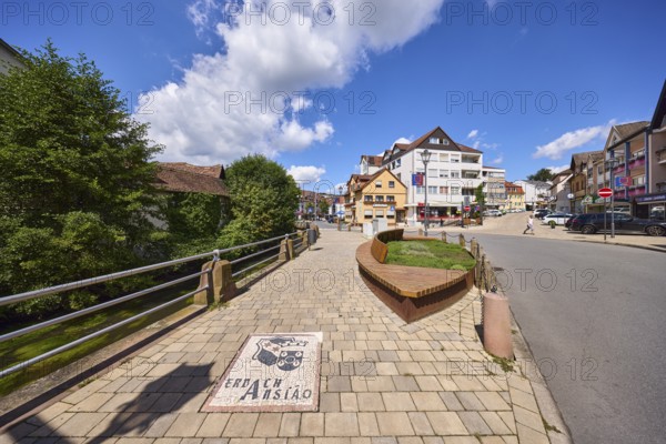 Bench, trees, blue sky with cumulus clouds, intersection of Hauptstraße and