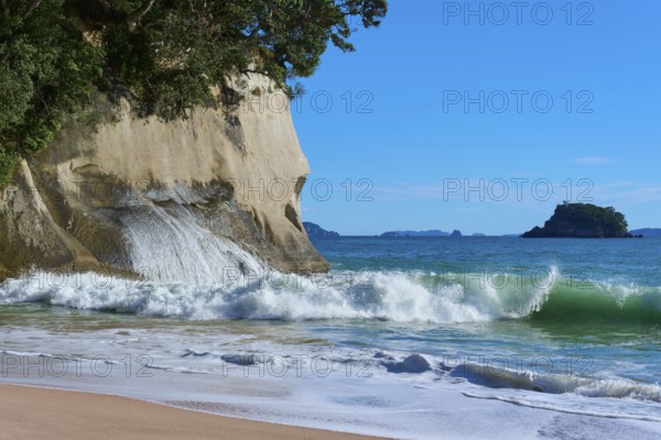 Waves crashing on a rocky coastline with splashing spray against a blue sea, Cathedral Cove, Hahei,