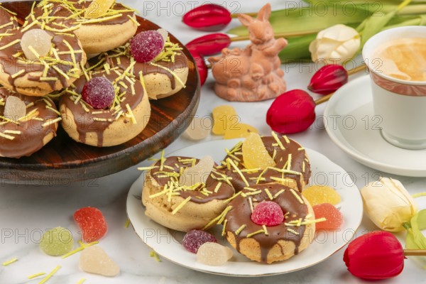 Decorated donuts next to coffee cup, Easter bunny, red tulips