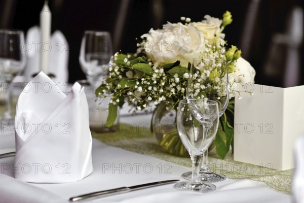 Beautiful white flower bouquets with drinking glasses and cloth napkin at Wedding table setting