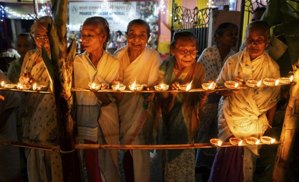 Elderly women of Pramod Talukdar Memorial Old Age Home light Diya oil lamps as they celebrate