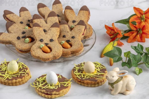 Bunny biscuits with carrots and egg decoration next to orange flowers and Easter bunny