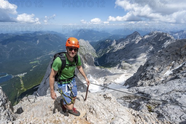 Mountaineer with helmet in a secured via ferrata, Zugspitze via ferrata, ascent to the Zugspitze,