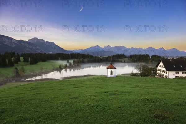 Idyllic mountain landscape with chapel and lake in the evening light, peaceful atmosphere, crescent