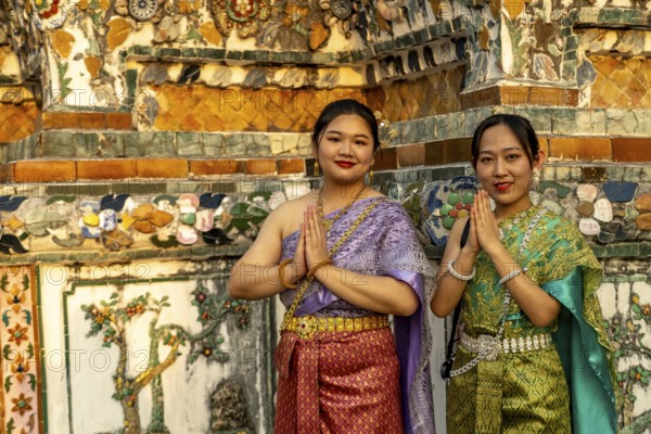 Traditionally dressed woman pose in front of the temple Wat Arun or Temple of Dawn in Bangkok,