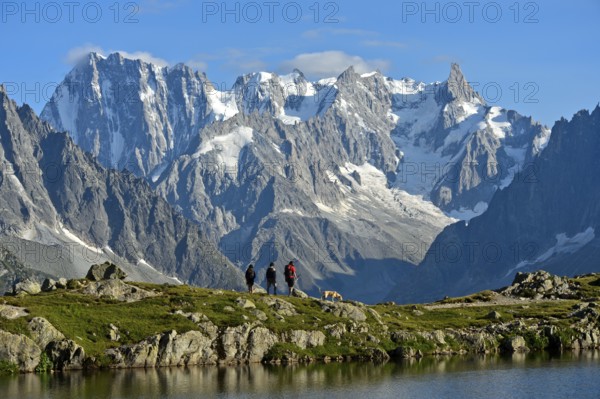 Hikers at the mountain lake Lacs des Chéserys in the Aiguilles Rouges nature reserve against the