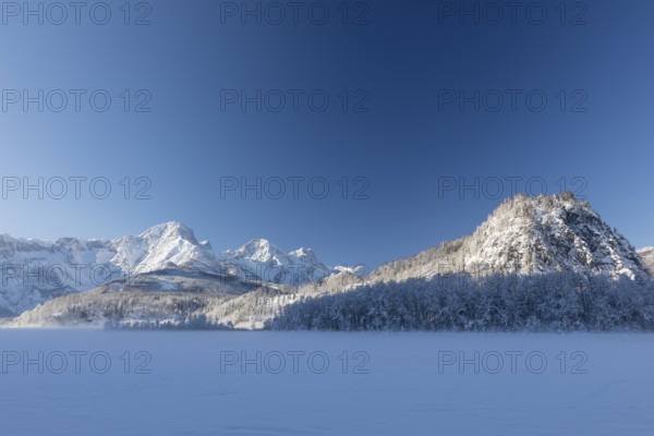 Ameisstein (776 m) mountain at the Lake Almsee in winter. The lake is frozen and snow covered,