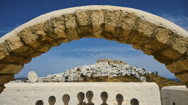 Stone arch frames the view of a hilltop village with a fortress, Querini Castle, Chora, Astypalea,