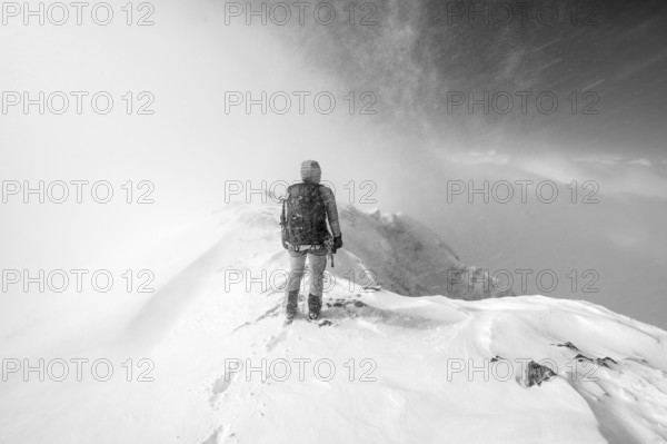 Ski tourer in snowy mountain landscape, at the summit of the Wildhorn, black and white photo,