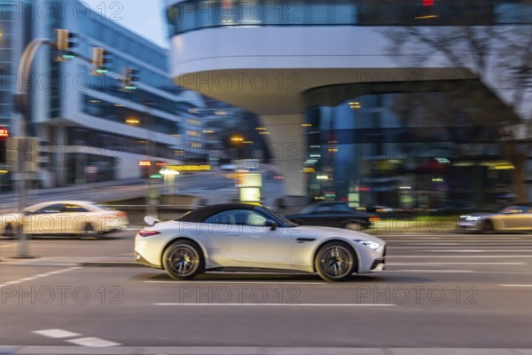 Car at night in front of urban surroundings with modern architecture, pull-along. Mercedes-Benz SL
