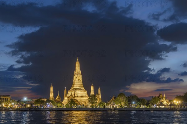 Wat Arun, Temple of Dawn at sunset with dark clouds. Boats on the Chao Phraya river. Tourist