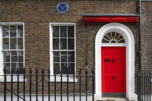 Red entrance door in a brick building with a cast-iron fence, Charles Dickens Museum, 48-49 Doughty