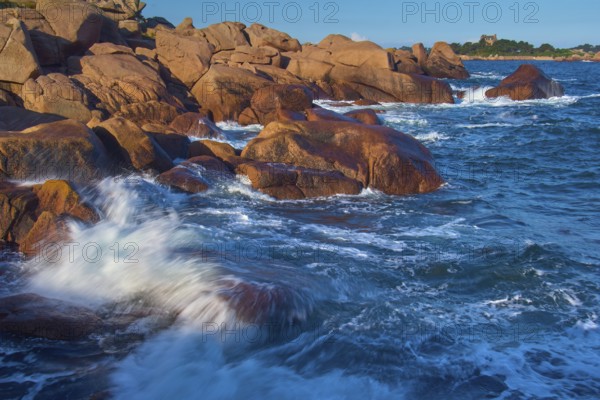Large rocks on the Granit Rose coast, lapped by the dynamic waves of the blue sea, Ploumanach, Cote