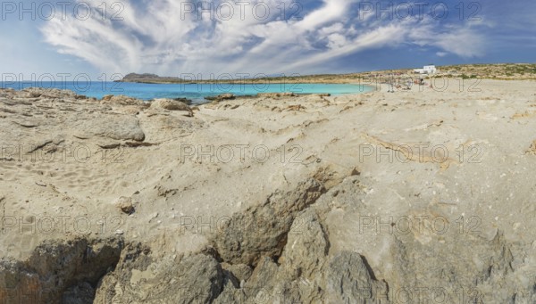 Rocks and sand meet the blue of the ocean under a wide, clear sky at Diakoftis Beach, Karpathos,