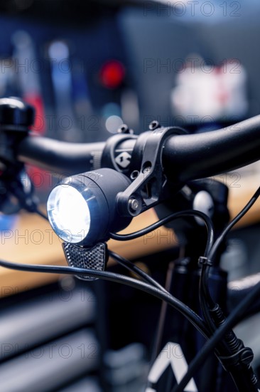 Bicycle light on the handlebars shines brightly in a workshop, focus on technological details,