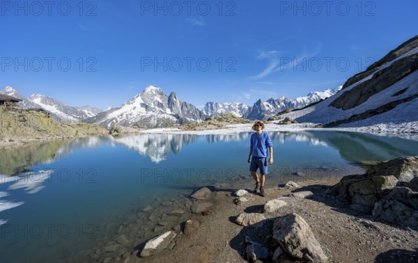 Mountaineer in front of mountain landscape with mountain lake, tourist at Lac Blanc with water