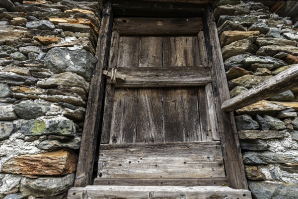 Old wooden door of a typical Ticino stone house in the mountain village of Bordei, Centovalli,