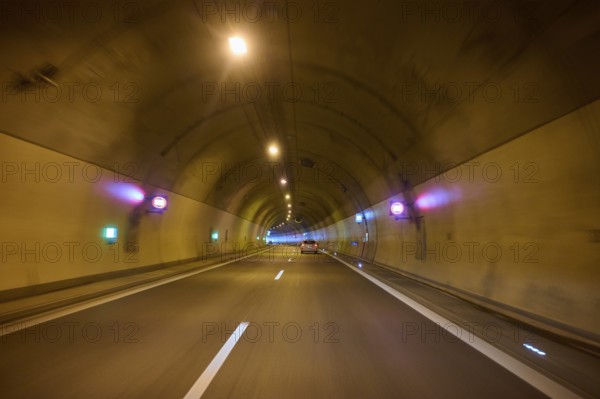 Illuminated motorway tunnel with several lights and signs, Switzerland, Europe
