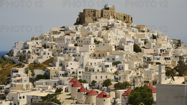 Whitewashed houses with red roofs and windmills under a stone castle, Querini Castle, Chora,