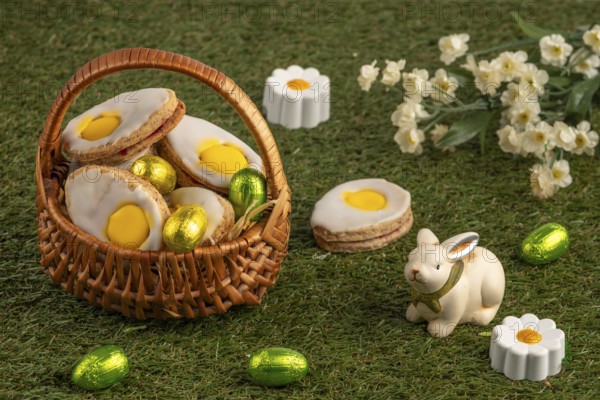 Easter biscuits in baskets with a bunny figure and flowers on a green lawn