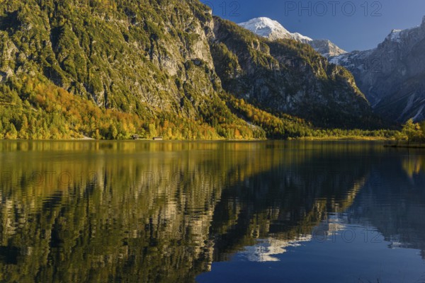 Lake Almsee in autumn with mountains reflected in the lake. Blue sky with no clouds