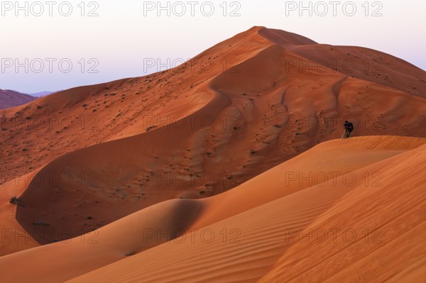 A photographer with a tripod in the wind-sculpted sand dunes in the Rub al Khali desert, Dhofar