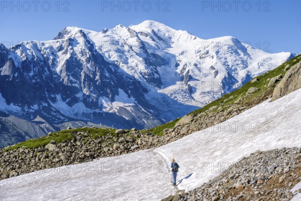 Mountaineer crossing a snowfield, view of spectacular glaciated peaks of Mont Blanc, Mont Blanc