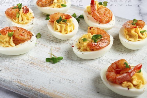 Boiled eggs stuffed with yolk and seasoned with mayonnaise, stuffed eggs with shrimp, on a white