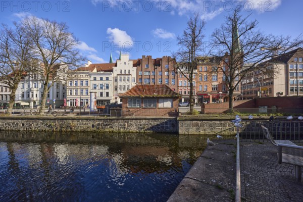River Trave, historic houses, blue sky with fair weather clouds, quay wall, railing, street An der