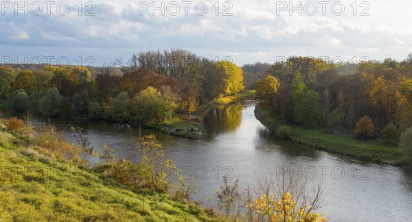 River, surrounded by autumnal trees and meadow landscape under a cloudy sky, confluence of the Elbe
