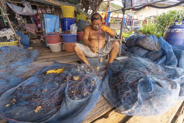 Fisherman repairing his net, fishing village Ban Ao Salad, island Ko Kut or Koh Kood in the Gulf of