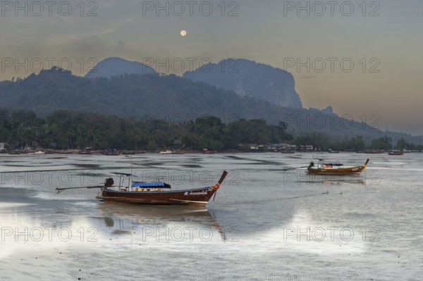 Before sunrise, longtail boats lie at low tide in the harbour at Sivalai Beach, Koh Mook Island,