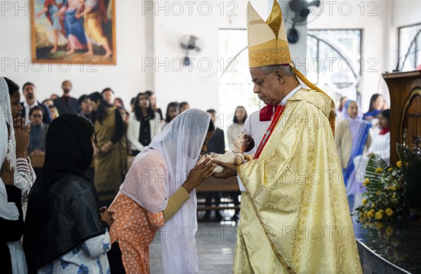 Archbishop John Moolachira holds an idol of baby Jesus Christ as devotees kiss the idol during a