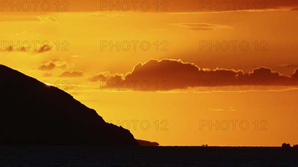 Melancholic coastal atmosphere at sunset with clear clouds over the sea, sunset, Kassos, Karpathos,