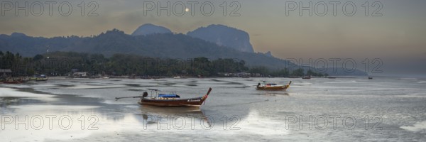Before sunrise, longtail boats lie at low tide in the harbour at Sivalai Beach, Koh Mook Island,