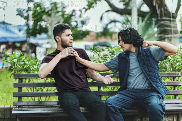 Two guys arguing sitting on a bench. Two male friends arguing on a park bench